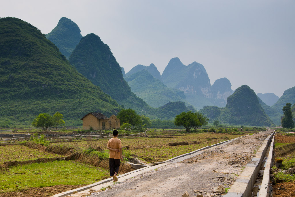 Chinese boy walinkg on a newly constructed road in ricefields in Guangxi