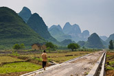 Chinese boy walinkg on a newly constructed road in ricefields in Guangxi